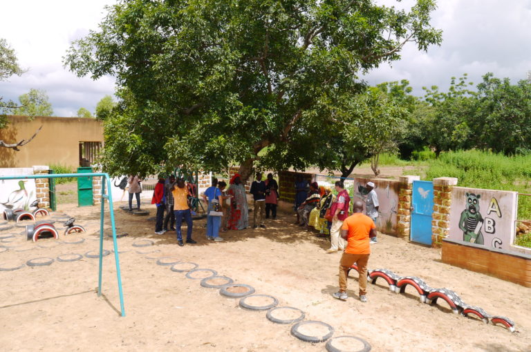 People meeting under a tree in a playground.