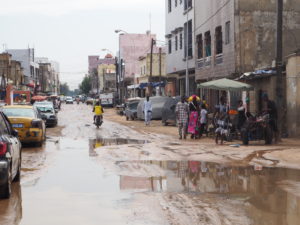 Route en terre après la pluie avec passants à pieds et une moto roulant au milieur